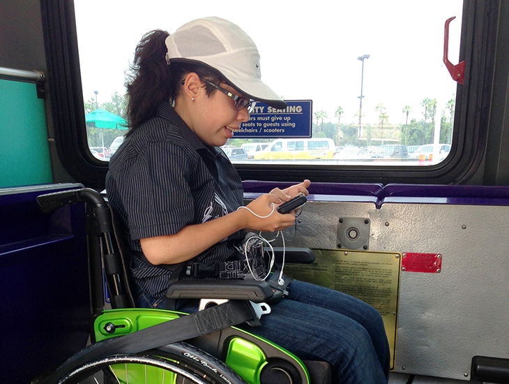 Woman in wheelchair uses her phone while riding bus.